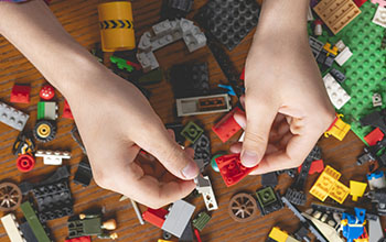male hands searching for suitable toy block on a wooden table